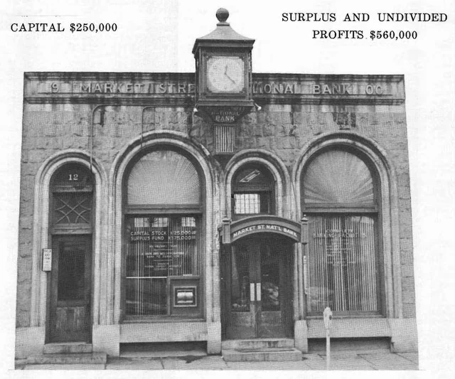 Black-and-white view of the arched stone Market Street National Bank facade with the number 12 over its side entrance