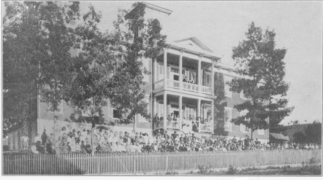 Historic black-and-white exterior photograph of Shamokin’s Old Academy with a large group gathered along the fence