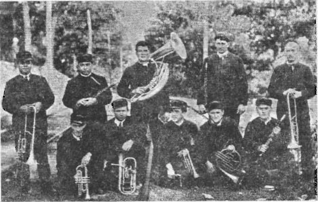 Black-and-white 1909 group portrait of ten Shamokin Band musicians holding brass instruments outdoors