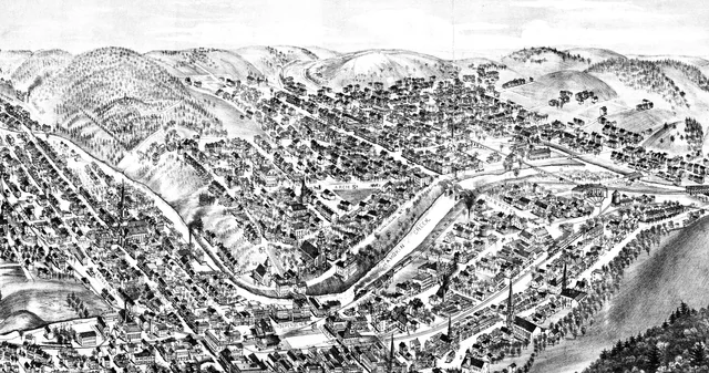 Oblique 1884 illustration of Shamokin with dense street blocks, bridges, creeks, rail lines, churches, and surrounding hills