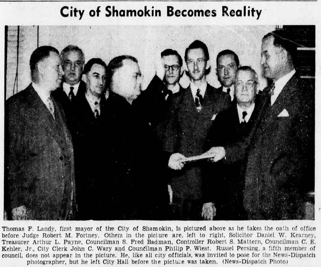 Thomas F. Landy taking an oath before Judge Robert M. Fortney while other city officials stand nearby, with the original newspaper caption below.