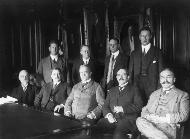 Nine committee members, four standing behind five seated, at NACA’s first meeting